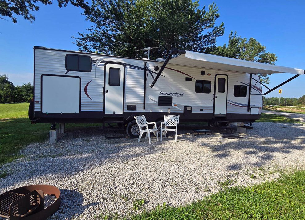 Fully furnished vacation rental camper at 4 Seasons RV Park in Mansfield, Missouri with outdoor seating, an awning, and a private fire ring.